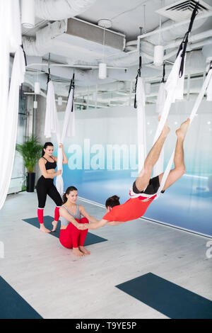 Formateur de Yoga assis sur le plancher et tenir la main de l'homme Banque D'Images