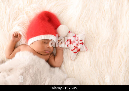 Mignon bébé Afro-américains à Santa Claus hat dormir sur Plaid fourrure blanche Banque D'Images