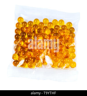 Ballon sphérique orange gélules d'huile de poisson dans un sac plastique isolé sur fond blanc. Banque D'Images
