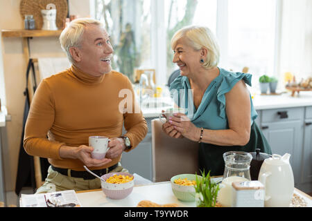 Cheerful couple marié le partage d'un rire tout en prenant le petit déjeuner Banque D'Images