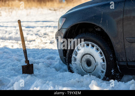 Coincé dans la voiture tout terrain de la neige à l'aube avec pelle et focus sélectif. Banque D'Images