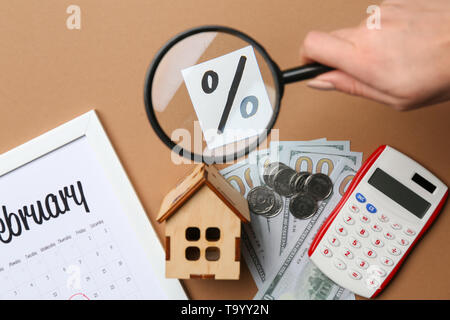 La main féminine avec loupe, calendrier, argent, calculatrice et signe pourcentage sur un fond de couleur. Concept d'hypothèques Banque D'Images