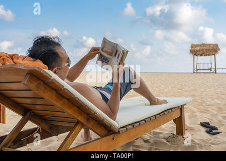 Jeune homme lecture livre sur la belle plage Banque D'Images