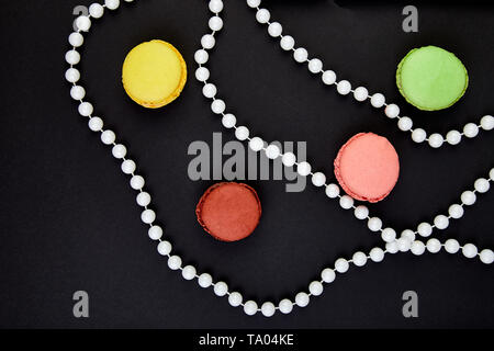 Un beau motif de macarons et des perles sur fond noir. télévision lay, vue d'en haut Banque D'Images