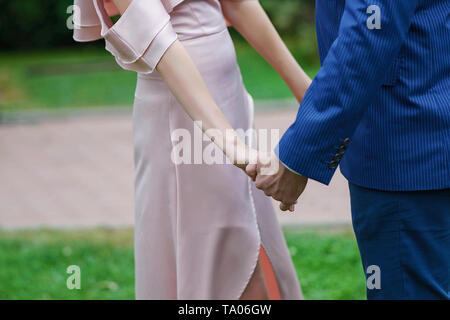 Couple, mariée en robe de satin ivoire et le marié en costume bleu foncé, avec la main un flou, out-of-focus contexte Banque D'Images