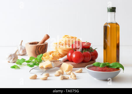 Table avec des ingrédients pour faire des tomates séchées. Tomates, ail, basilic et origan frais herbes, bouteille d'huile d'olive, quelques noix de cajou, fromage parmesan, c Banque D'Images