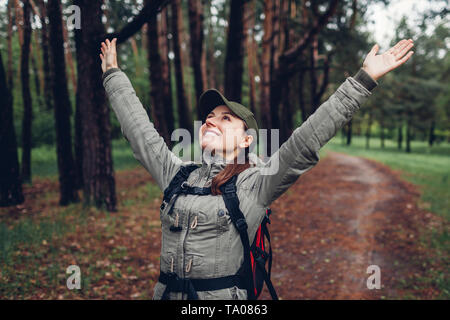 Heureux touriste sac à dos avec la marche dans la forêt de printemps et de se sentir libre d'armes. Voyages et tourisme concept Banque D'Images