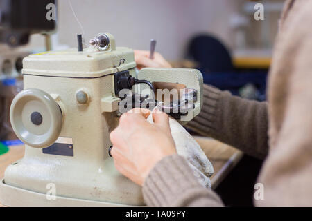 Professionnel hommes skinner, fourreur à l'aide de la machine à coudre spéciale pour coudre la peau de fourrure à l'atelier, atelier. La mode et le travail du cuir concept Banque D'Images
