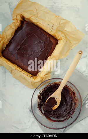 Préparation des délicieux carrés au chocolat noir humide végétalien sain brownies dessert ou gâteau avec glaçage café sur fond gris Banque D'Images