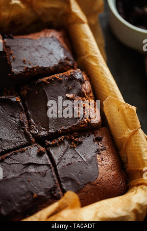 Delicious fresh baked végétalien sain sombre humide brownies au chocolat dessert ou gâteau avec glaçage café coupé en carrés sur du papier sulfurisé (top view Banque D'Images