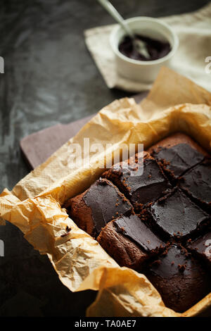 Delicious fresh baked végétalien sain sombre humide brownies au chocolat dessert ou gâteau avec glaçage café coupé en carrés sur un fond sombre Banque D'Images