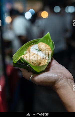 Kanom Krok, la crêpe coco thai, enveloppés dans des feuilles de bananier dans les mains d'une femme sur le marché de nuit de Chiang Mai, Thaïlande Banque D'Images