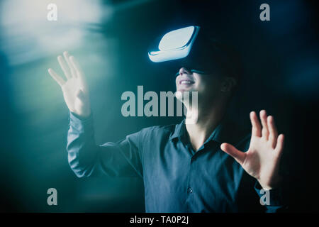 Image composite d'un homme portant un casque VR en interaction avec un environnement virtuel simulé avec du flare Banque D'Images