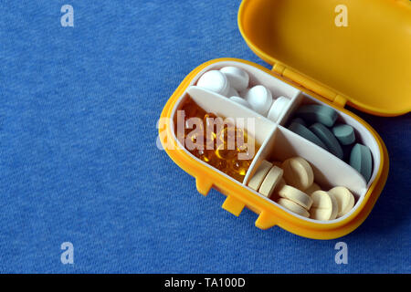 Médicament en plastique jaune contenant avec pills sur fond bleu. Copy space Banque D'Images