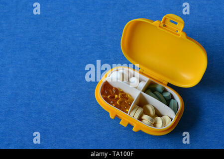 Médicament en plastique jaune contenant avec pills sur fond bleu. Copy space Banque D'Images