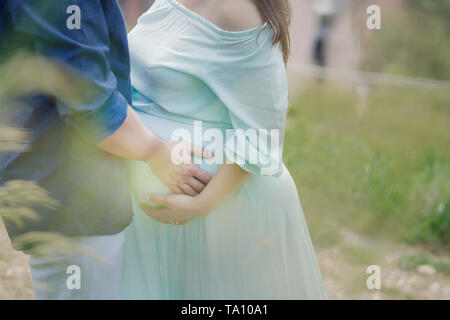 Cropped shot of handsome Young couple holding hands avec accent sur la femme enceinte belle ronde du ventre, le concept de famille heureuse s'attendant Banque D'Images