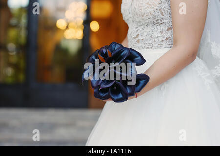 Prune noire sophistiquée des zantedeschias bridal bouquet, l'accessoire parfait pour un effet mystérieux et majestueux, gros plan sur les mains de la mariée Banque D'Images