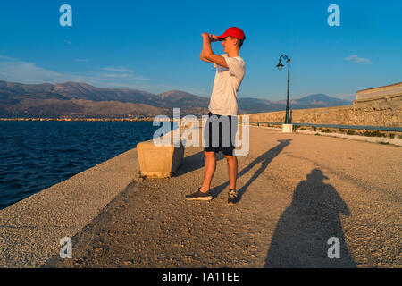 Jeune homme regarde dans le soleil couchant Banque D'Images