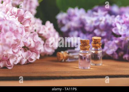 Bouteilles d'huile essentielle et lilas fleurs sur table en bois Banque D'Images