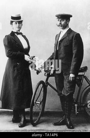 Cycliste élégant couple dans "vêtements" étoffé. La location dispose d'une lampe à carbure en face. Photo non datée. Banque D'Images