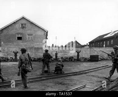 Les soldats de la 157e Régiment d'infanterie de l'armée américaine sont ciblant les hommes, qui sont SS alignés le long d'un mur. Selon la légende originale, le SS hommes couchés sur le terrain d'essayer de faire semblant d'être mort après que les Américains ont ouvert le feu sur un fuyant la garde. Dans une action de vengeance spontanée entre 39 et 50 gardes ont été tourné et cette photo montre probablement le moment avant l'exécution. Banque D'Images