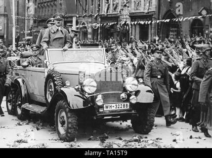 Adolf Hitler entrant dans le Cheb Sudètes. Le cortège du Hitler est reçu par les acclamations de la population. Ils saluent avec le salut nazi. L'adjudant Rudolf Schmundt est assis sur le côté gauche de la voiture, des gardes du corps de la SS sont la marche à côté de la voiture. Banque D'Images