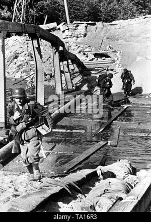 Trois soldats allemands d'une équipe radio traverser un pont détruit sur le front de l'Est (Lieu inconnu, probablement dans le Belarus). En plus des débris, des soldats soviétiques morts gisent sur le reste du pont. Photo de l'entreprise de propagande (PK) : correspondant de guerre Weber. Banque D'Images