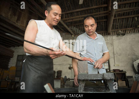 (190521) -- LONGQUAN, 21 mai 2019 (Xinhua) -- Zheng Guorong (L) et son collègue Wu Changyou discuter épée galetage de compétences Compétences à l'Épée 8090 Studio dans l'est de la Chine, Longquan Zhejiang Province, le 21 mai 2019. Pendant des siècles, Longquan a été célèbre pour son épée. Zheng Guorong, 55, un patrimoine culturel immatériel de l'héritière dans Longquan sabre, épée a fait depuis plus de 30 ans. Zheng ce qui concerne l'épée comme un symbole de l'esprit et consacre toute sa carrière avec admiration. Dans son studio, l'ensemble du processus de décisions d'une seule épée prend de deux à trois mois, avec des étapes includin Banque D'Images