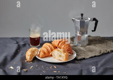 Matin petit déjeuner avec des croissants croustillants faits maison française sur une plaque avec du café fraîchement moulu parfumé sur un fond textile foncé. S COPIE Banque D'Images
