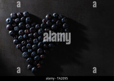 Les bleuets en forme de coeur. Moody et sombre. lumière intentionnelle Élégant contemporain moderne de droit d'aliments sains. Banque D'Images