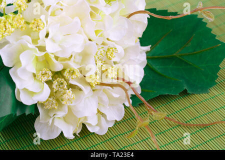 Fleurs en tissu blanc sur fond de bambou, gros plan photo. Banque D'Images