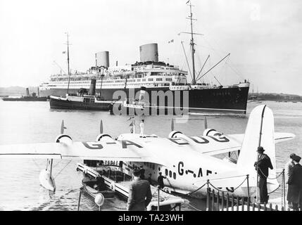 Le bateau à vapeur rapide de "Europa" est de la Norddeutscher Lloyd dans le port de Southampton. Au premier plan, l'hydravion Empire courte G-AEUG Coogee de l'Imperial Airways. Sur le côté gauche de l'hydravion est un radeau, sur lequel les passagers peuvent embarquer. Banque D'Images