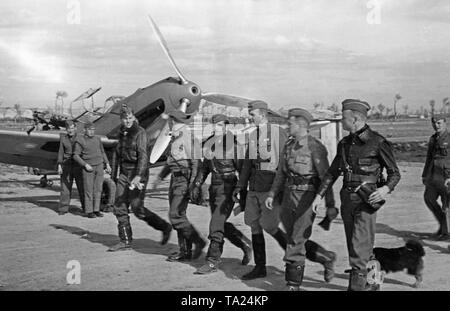 Photo d'un groupe de pilotes de combat de la légion Condor, groupe de combat 88, en marchant à leur prêt-à-utiliser Messerschmitt Bf 109 combattants (à l'arrière-plan) sur un aérodrome en Espagne en 1939. La bouche de la mitrailleuse est visible dans le creux de l'hélice et le cône de. Banque D'Images
