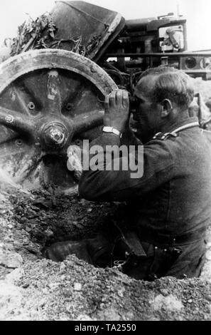 Un soldat allemand surveille les positions de l'ennemi d'une carabine fosse. À côté de lui un canon antichars (probablement une 7,5 cm PaK-40). Photo de l'entreprise de propagande (PK) : correspondant de guerre Kraayvanger. Banque D'Images