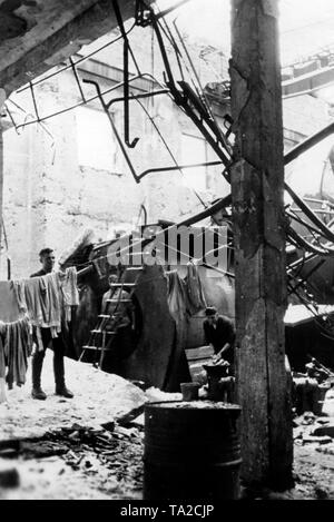 Soldats allemands dans leur bunker 'U-Boot' dans une usine près de détruits. Volkhov Ils utilisent une chaudière à vapeur détruit comme base. L'un des soldats se bloque sur une ligne de blanchisserie. Photo de l'entreprise de propagande (PK) : correspondant de guerre Wolkenstoerfer. Banque D'Images