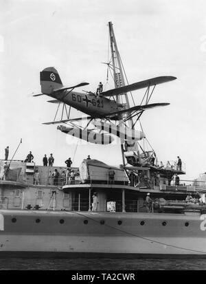 Au cours d'une revue navale à Swinemuende, le croiseur 'Nuremberg' prend une embarcation à bord avec sa grue. L'aéronef est un Heinkel He 60. Banque D'Images