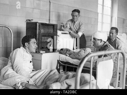 Photo non datée de quatre blessés soldats allemands de la légion Condor à écouter la radio dans un service d'un hôpital militaire pendant la guerre civile espagnole. Les soldats portent des pyjamas ou blouses et champs sont légèrement blessés. Banque D'Images