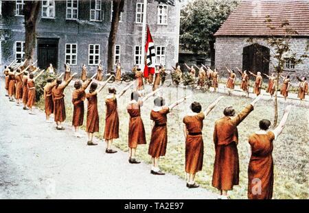 Les filles au cours de la BDM daily morning roll call hissant le drapeau à croix gammée sur le parvis d'un Landjahrheim du NSDAP. En 1939, l'année obligatoire a été introduite pour la plupart des filles allemandes et les femmes de moins de 25 ans. Banque D'Images