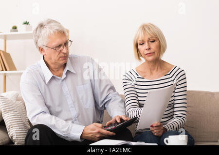 Inquiets Senior Couple contrôler leurs factures à la maison Banque D'Images