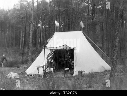 Le jeune prince Frederick William, plus tard l'empereur Guillaume II, se dresse sur une manœuvre dans l'uniforme du 1er régiment de Hussard n° 1 à l'entrée d'une tente d'une nuit en camp en face d'une forêt de pins. En haut de la tente la nuit il y a des drapeaux de Prusse (noir et blanc). Gauche de l'entrée, les tables et les tabourets avec buanderie et des bouteilles de vin. Sur la gauche, un soldat est le brossage des dents vêtus de pantalons de la tuyauterie. Photo prise probablement dans la matinée. Banque D'Images