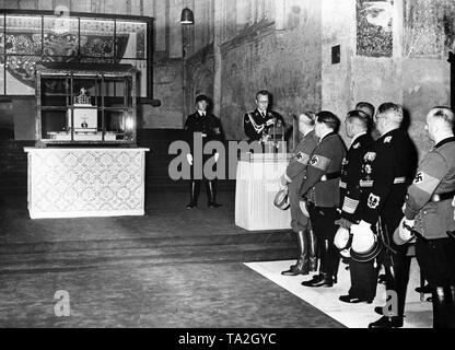 Les Regalia impériales (Reichskleinodien) est remis au maire de Nuremberg, Maire Willy Liebel, par l'Autrichien Reich gouverneur Arthur Seyss-Inquart (au pupitre) dans la Katharinenkirche (St. Catherine's Church) à Nuremberg, où elles sont également exposées. Avant de Seyss-Inquart, à l'écouter (de gauche) : Hanns Kerrl, Wilhelm Ohnesorge, Generaladmiral Erich Raeder, Ministre d'Etat Dr. Otto Meissner. À la gauche de Seyss-Inquart, un garde de la SS. Banque D'Images