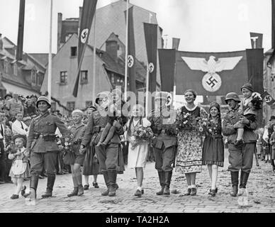 Selon l'accord de Munich, les Sudètes est annexé à l'Empire.Les soldats de la Wehrmacht dans les rues de sudètes allemandes qu'il soit accompagné d'enfants. Banque D'Images