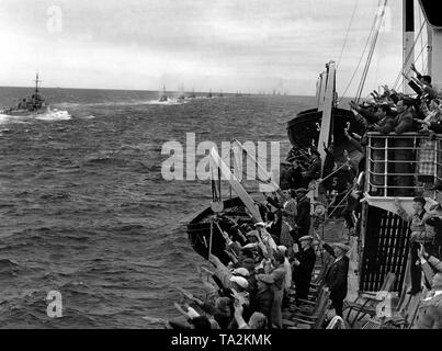 Les vacanciers à bord du bateau de croisière "Der Deutsche' de l'organisation Nazie "Kraft durch Freude" ('force par la joie") acceptent avec enthousiasme montrant le salut nazi à la guerre, les navires de la Kriegsmarine, qui voile par en ligne. Après son retour de Norvège, une partie de la Hochseeflotte Allemande (flotte) est d'effectuer une manœuvre avec les navires de croisière de la KdF 'Wilhelm Gustloff', 'Der Deutsche' et 'Berlin'. Banque D'Images