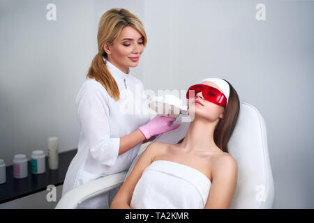 Médecin esthétique laser rajeunissement pour faire RF attrayante jeune femme au salon de beauté. Elos épilation cosmetological procédure. Faciale esthétique Banque D'Images