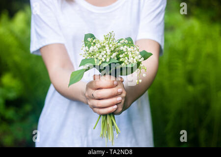 Woman holding joli bouquet de fleurs de la vallée de lilly contre fond vert vif Banque D'Images