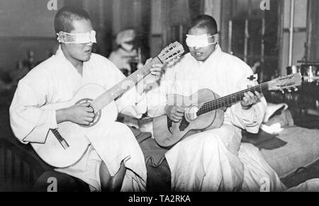 Deux blessés soldats japonais jouer de la guitare dans un hôpital militaire. Les deux d'entre eux ont perdu leurs yeux dans la Seconde Guerre Japanese-Chinese. Leurs yeux sont bandées. Banque D'Images