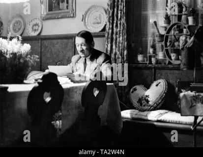 Adolf Hitler se lit une lettre dans la salle à manger de sa maison de campagne 'Wachenfeld' Obersalzberg. À droite sur le banc est un oreiller sous la forme d'un coeur. Banque D'Images