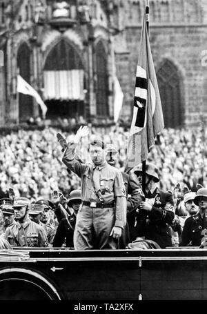 Adolf Hitler dans la voiture au Reich Partie rallye de la NSDAP à Nuremberg au cours des mois de mars de la SA des associations. Derrière lui, c'est Ernst Roehm. Également dans l'image le drapeau 'Blood', tenu par Adolf Grimminger. Probablement le 3.9.1933 sur la place du marché de Nuremberg. Banque D'Images