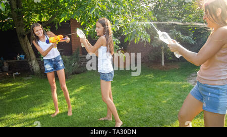 Image enfants jouant dans la chambre jardin arrière avec les pistolets à eau et d'arrosage. Le jeu et le plaisir de la famille à l'extérieur à l'été Banque D'Images