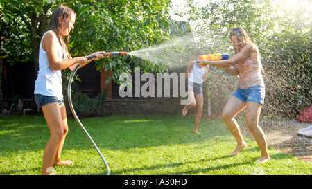 Image enfants jouant dans la chambre jardin arrière avec les pistolets à eau et d'arrosage. Le jeu et le plaisir de la famille à l'extérieur à l'été Banque D'Images